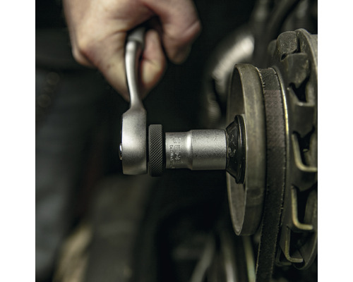 Hand met ratel en dop bezig met werkzaamheden aan een motor