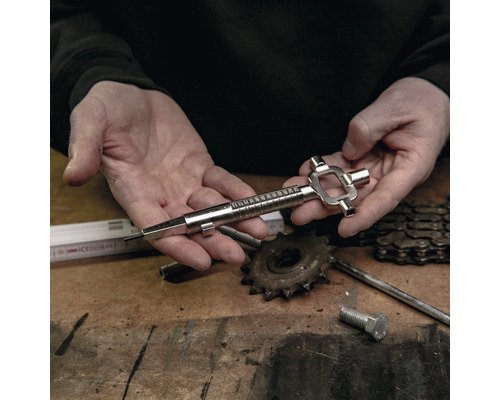 Een persoon houdt een metalen kettingverslijtagegereedschap voor fietsen in zijn handen