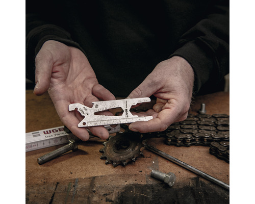 Man houdt een universeel gereedschap in zijn handen voor een werkbank met gereedschap.