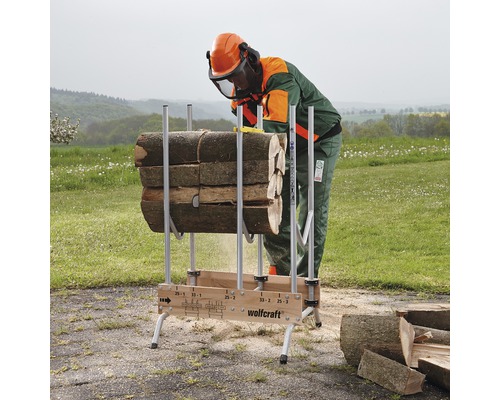 Een persoon met beschermende kleding zaagt hout op een Wolfcraft zaagbok.