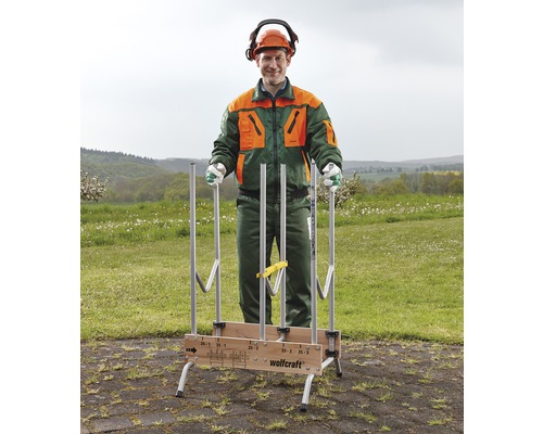 Een man met beschermende kleding staat achter een houtopslag van Wolfcraft die buiten staat.