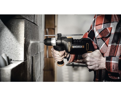 Een persoon boort met een Worx klopboormachine in een bakstenen muur.