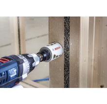 Boormachine met Bosch gatenzaag boort een gat in een houten plank.