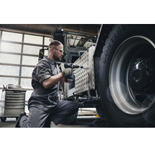 Een monteur werkt met een accuboormachine aan een voertuig.