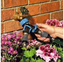 Tuinslangadapter bevestigd aan een kraan voor tuinbesproeiing.