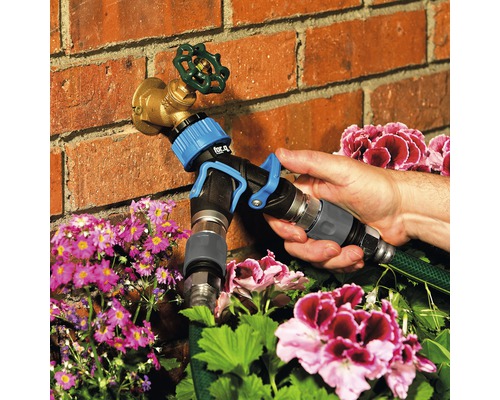 Tuinslangadapter bevestigd aan een kraan voor tuinbesproeiing.