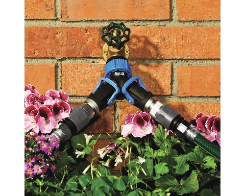 Waterkraan met verdeler en aangesloten tuinslangen voor een bakstenen muur