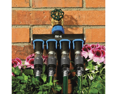 for.q-verdeelstuk met vier aansluitingen en aangesloten tuinslangen voor een bakstenen muur