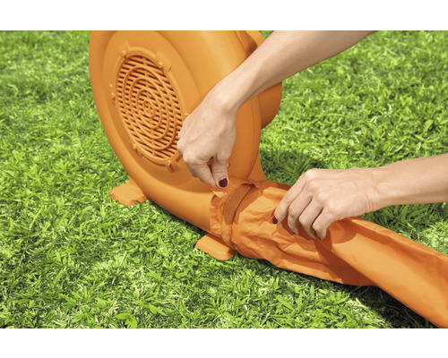 Een persoon bevestigt de slang aan een blaasmachine in de tuin.