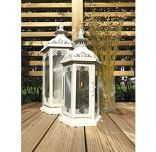 Twee witte lantaarns van metaal en glas op een houten terras, daarnaast een glazen vaas met droogbloemen