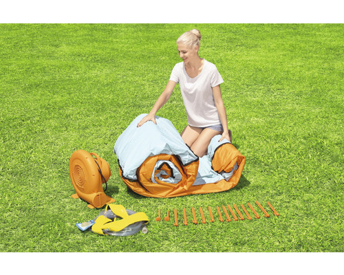 Vrouw zet een opblaasbaar springkussen in de tuin op, inclusief ventilator en haringen