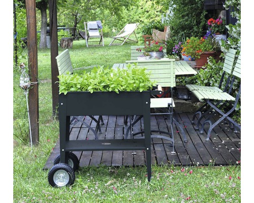 Tuinscene met plantenbak, tuintafel en tuinstoelen op een houten terras