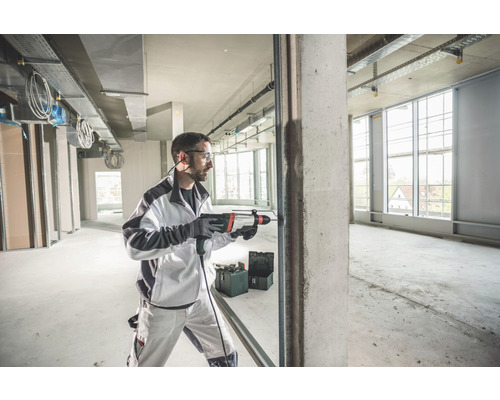 Man boort met een boorhamer een gat in beton in een casco.