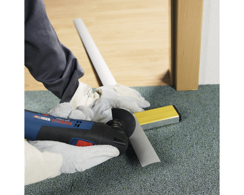 Ambachtsman snijdt plint met multifunctioneel gereedschap. Waterpas ligt klaar.