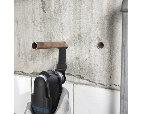 Multifunctioneel gereedschap snijdt koperen buis op een muur