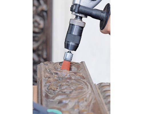 Boormachine met borstelopzetstuk reinigt een houten ornament