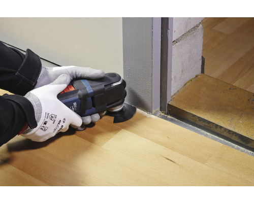 Persoon gebruikt multitool om te zagen op houten vloer