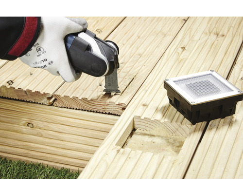 Oscillerend elektrisch gereedschap dat een houten terras snijdt voor een inbouw grondspot