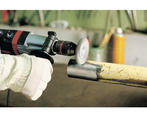 Iemand gebruikt een boormachine met een staalborstelopzetstuk op een buis om roest te verwijderen.