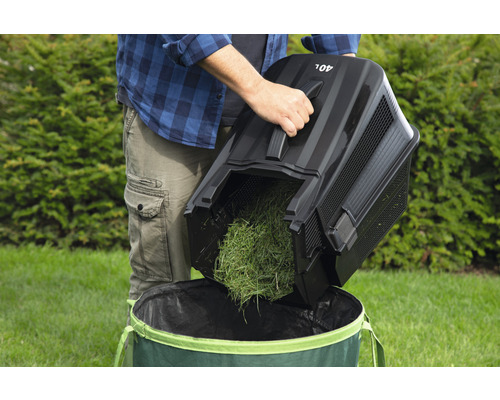 Iemand leegt een grasopvangbak van 40 liter in een tuinzak.