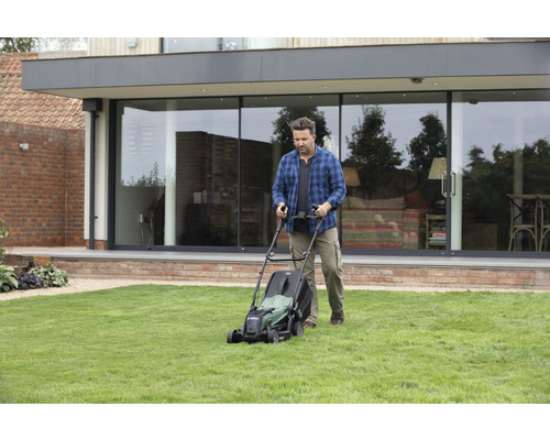Man maait gazon met een grasmaaier in de tuin voor het huis.