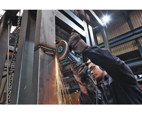 Een werknemer gebruikt een haakse slijper om metaal te bewerken, waarbij vonken ontstaan.