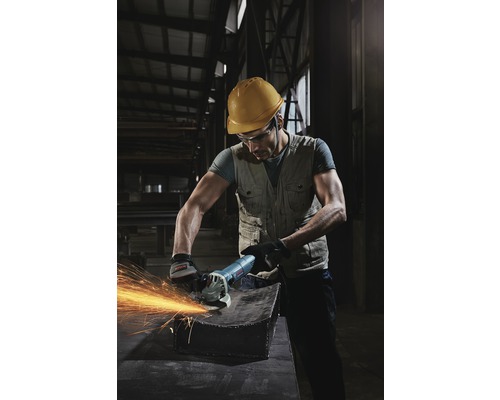 Een arbeider met veiligheidshelm en veiligheidsbril gebruikt een haakse slijper op een stuk metaal, waarbij vonken ontstaan.