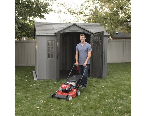 Man met grasmaaier voor een grijs tuinhuis