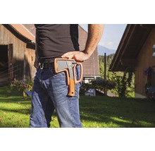 Persoon met bijl in holster aan riem in buitenopname.