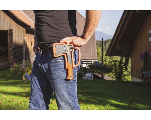 Persoon met bijl in holster aan riem in buitenopname.