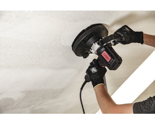 Een man schuurt een plafond met een plafondschuurmachine.