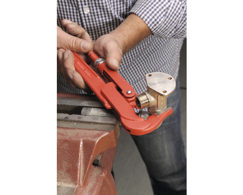 Een persoon bevestigt een messing fitting met een pijptang aan een bankschroef.