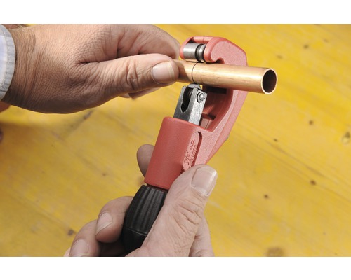 Een koperen buis wordt bewerkt met een pijpsnijder.