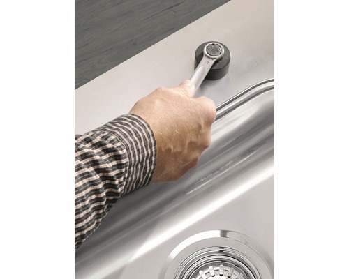Een hand met een steeksleutel bevestigt een magnetische houder aan een spoelbak.
