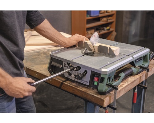 Persoon bedient tafelcirkelzaag met werkstuk en hoekaanslag. Bosch logo.