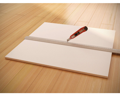 Hardschuimplaat met liniaal en stanleymes op houten vloer