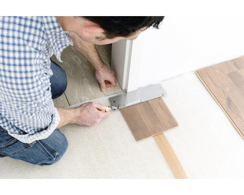 Man snijdt laminaat met een zaag bij een deurkozijn