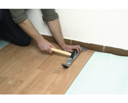 Laminaat leggen met een trekijzer en hamer