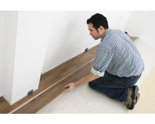 Man legt laminaatvloer binnenshuis met afstandhouders.