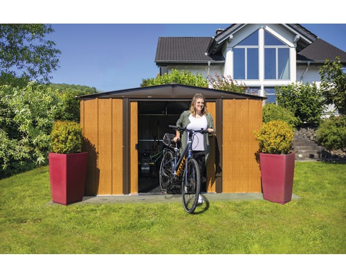 Tuinhuis met dubbele deur en een vrouw met fiets in de tuin