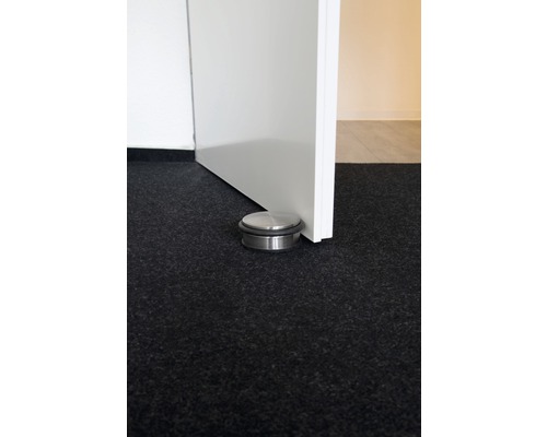 Metalen deurstopper op de vloer naast een deur