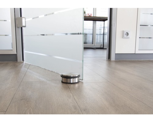 Deurstopper van roestvrij staal op houten vloer voor een glazen deur