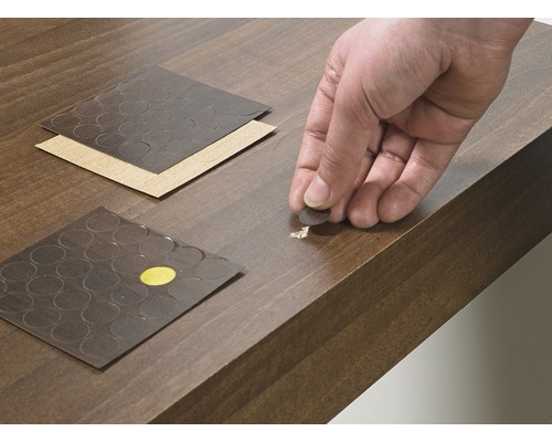 Reparatiestickers worden op een beschadigd houten oppervlak aangebracht.