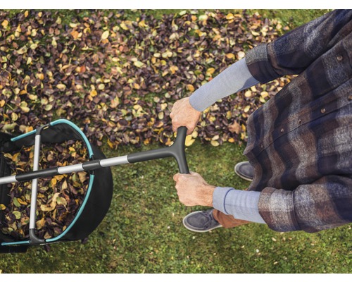 Bovenaanzicht van een persoon met een bladverzamelaar op een gazon met herfstbladeren