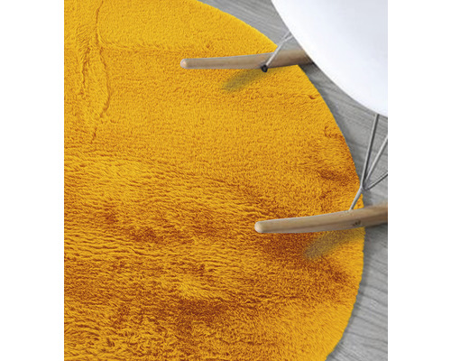 Detail van een rond, harig vloerkleed naast een stoel