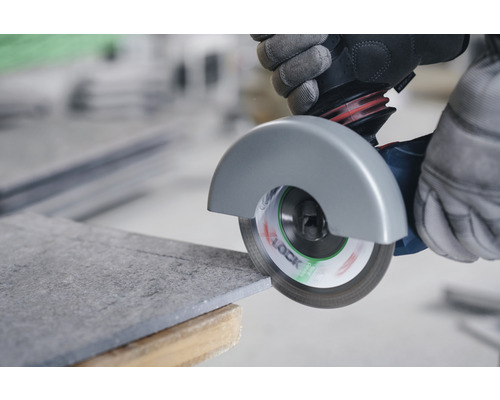 Iemand snijdt een tegel door met een haakse slijper