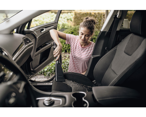 Vrouw stofzuigt autostoelen met stofzuiger