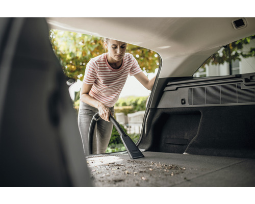 Vrouw stofzuigt de kofferbak van een auto met een stofzuiger