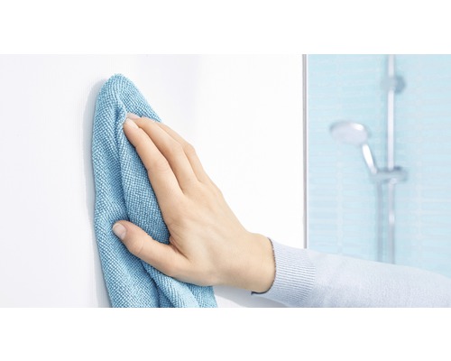 Een hand veegt een wit oppervlak schoon met een reinigingsdoek in een badkamer.
