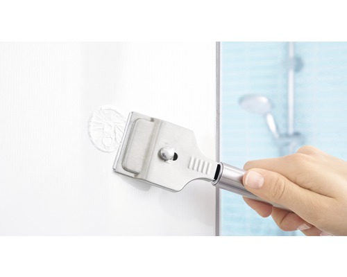 Hand gebruikt glasschraper om stickers te verwijderen in een badkamer.